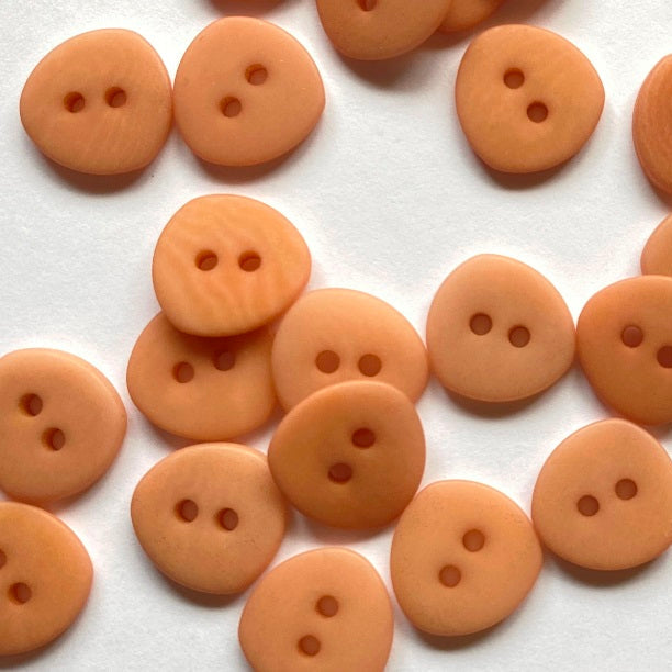 Collection of peach-colored buttons on a white background