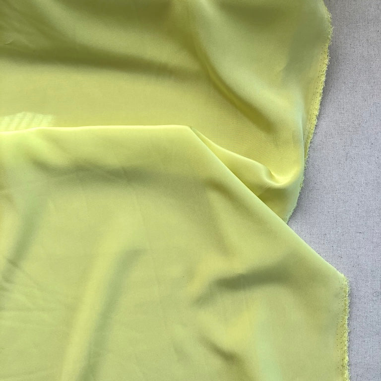 Close-up of light silk green fabric on a textured surface