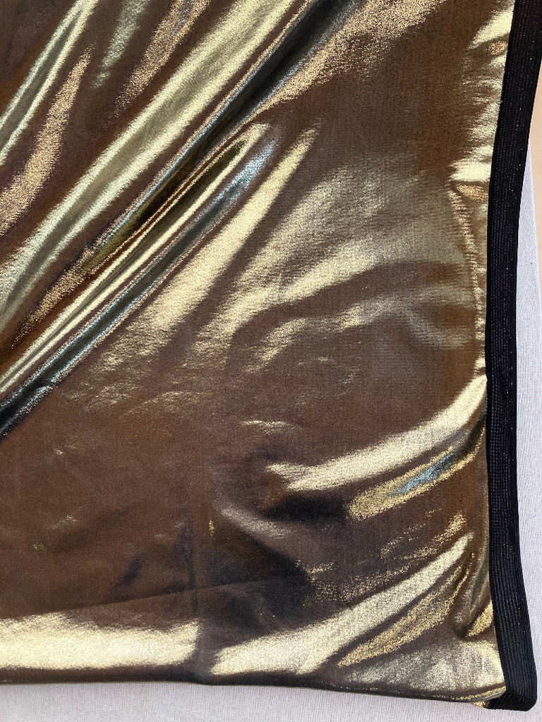 Close-up of a metallic gold fabric with a black border on a white background