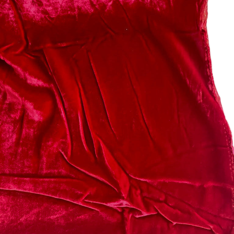 Close-up of red velvet fabric with folds on a light green background