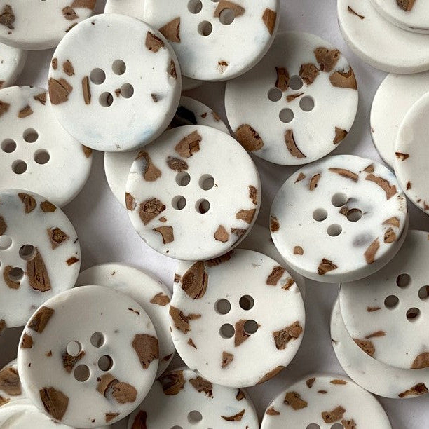 White buttons with brown speckles on a white background