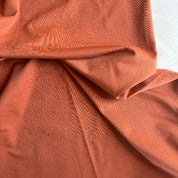 Close-up of rust-colored fabric with folds on a white background