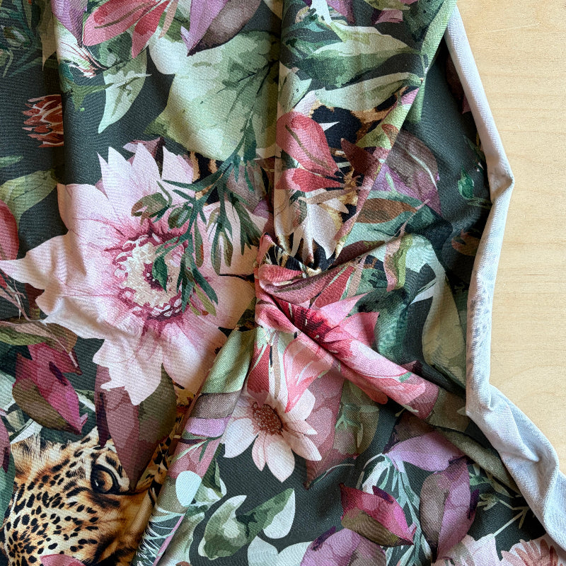 Floral fabric with pink and khaki flowers on a wooden surface