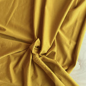 Close-up of ochre yellow fabric with folds on a light background