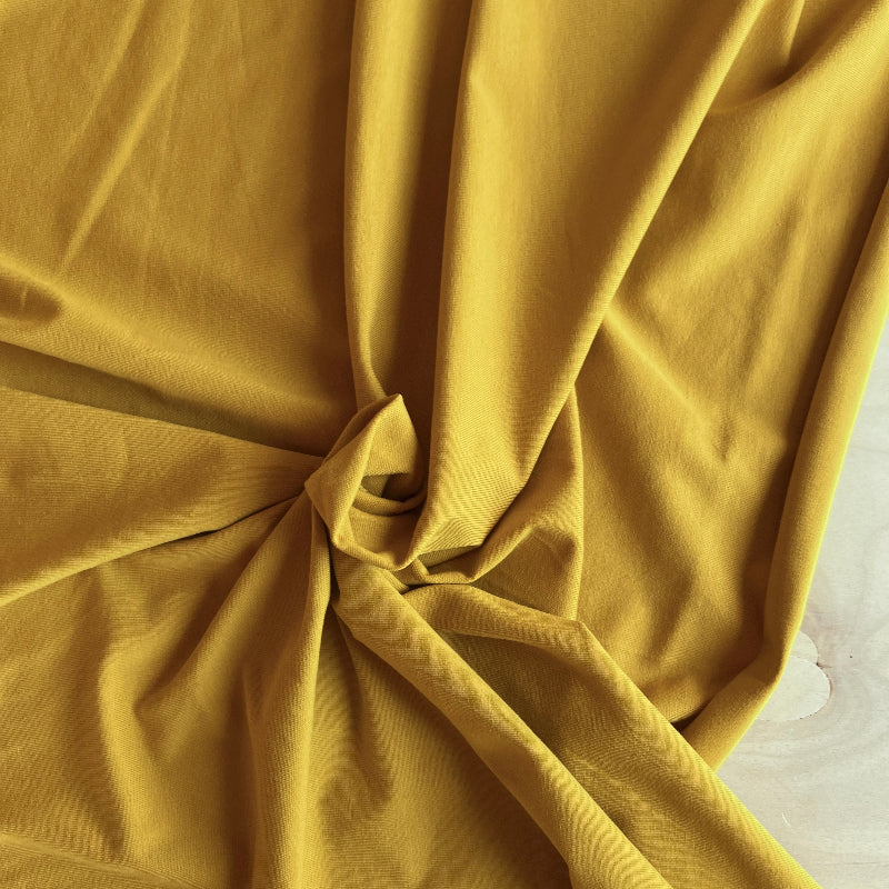 Close-up of ochre yellow fabric with folds on a light background