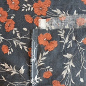 Floral fabric with orange flowers and green leaves on a dark blue background