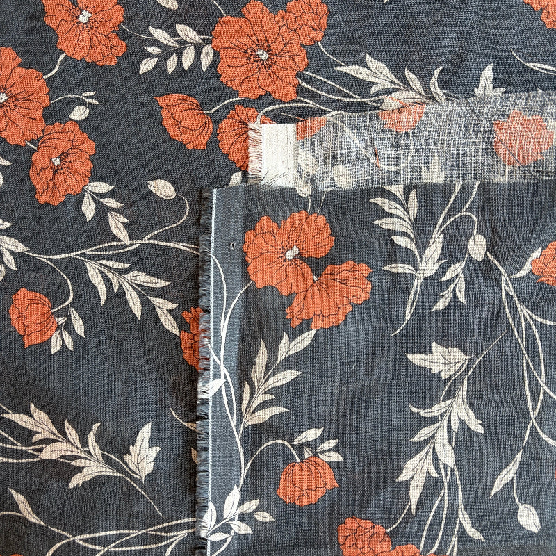 Floral fabric with orange flowers and green leaves on a dark blue background
