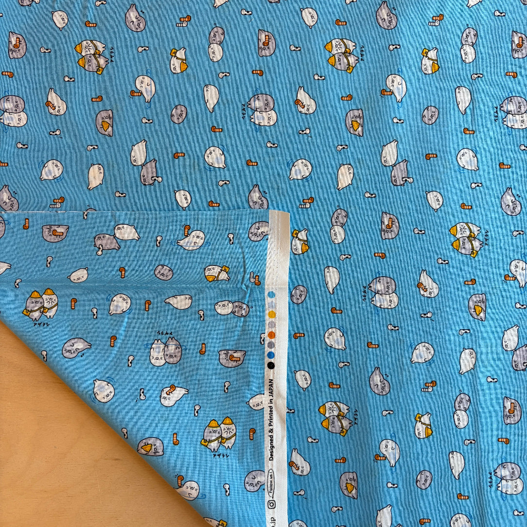 Blue fabric with cartoon character pattern and a ruler for scale on a wooden surface