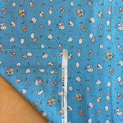 Blue fabric with cartoon character pattern and a ruler for scale on a wooden surface