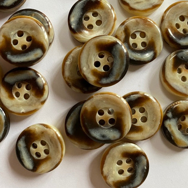 Collection of brown buttons with a four-hole design on a light pink background