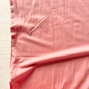 Close-up of pink fabric with a needle on a white background