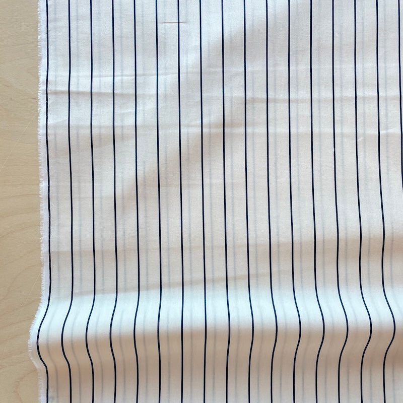 White fabric with black vertical stripes on a neutral background