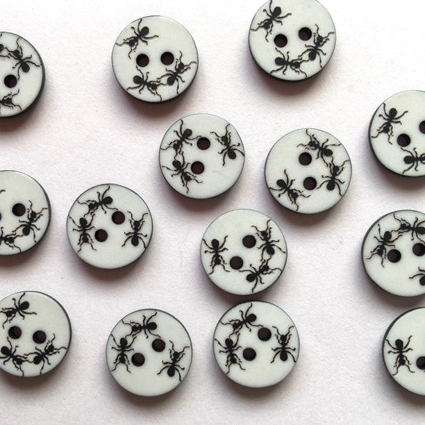 White buttons with black ant patterns arranged on a white background
