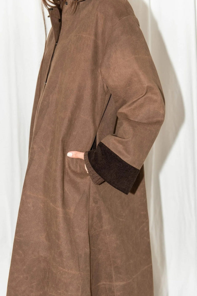 Brown coat worn by a person against a white background