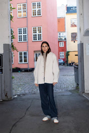 Woman standing in an urban setting with colorful buildings in the background