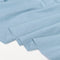 Light blue fabric draped in soft folds over a plain white background.
