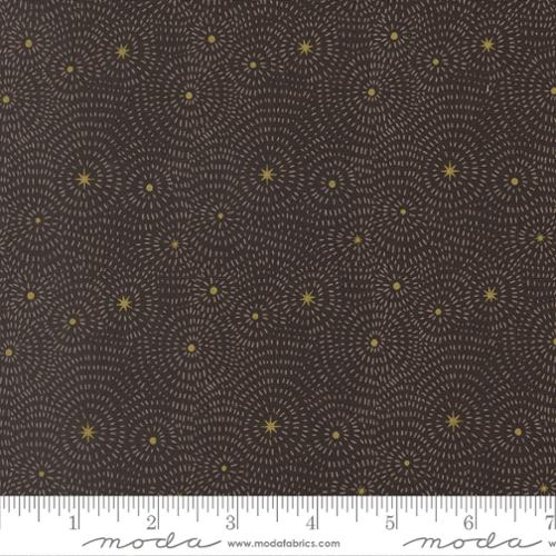 Fabric with gold stars radiating out small white lines on a black background with a ruler at the bottom.