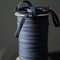 A spool of dark navy blue cord or ribbon with a few loose strands draped over the top, set against a dark gray background.