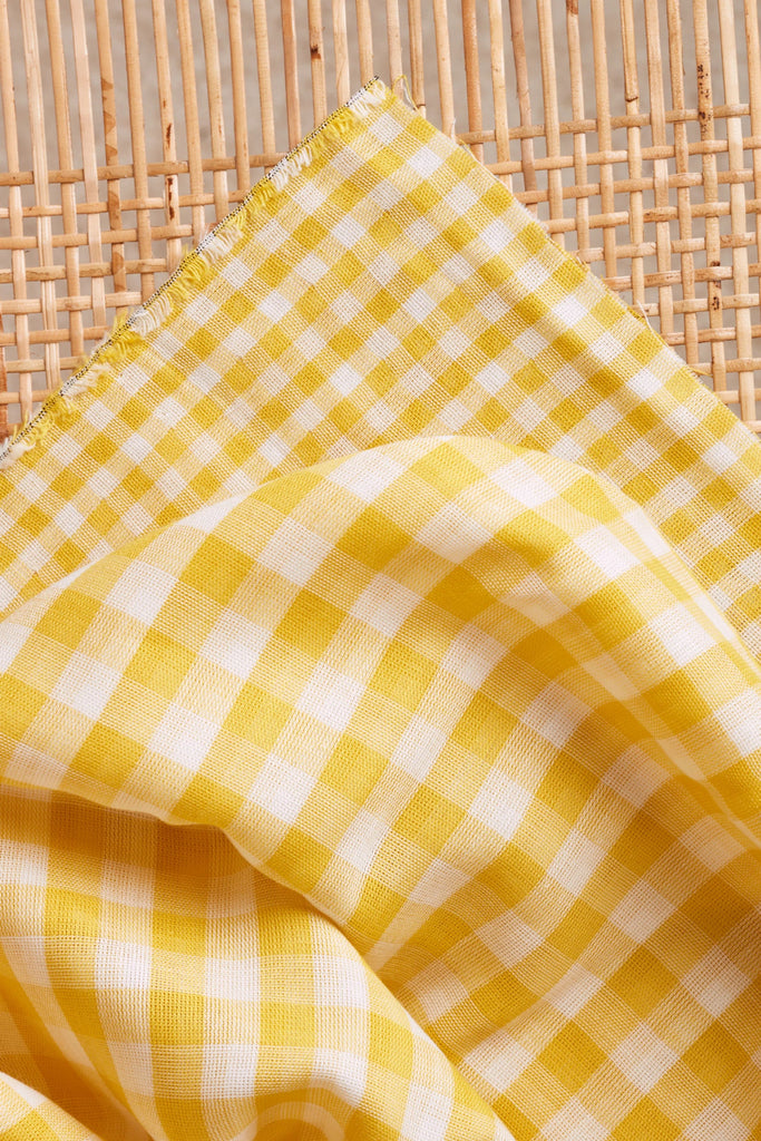 Yellow and white checkered fabric on a woven surface