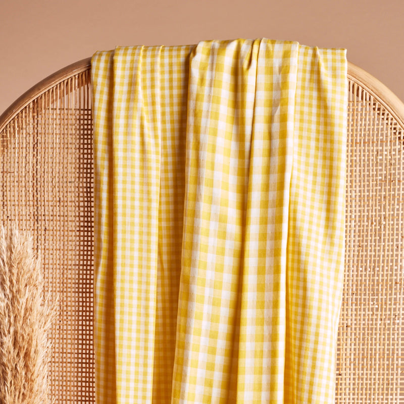 Yellow checkered fabric draped over a wicker chair on a beige background