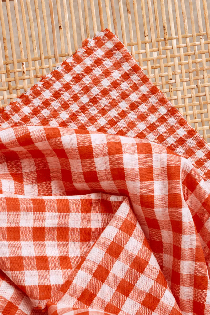 Orange and white checkered fabric on a woven surface