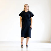 person wearing a black dress standing against a white background