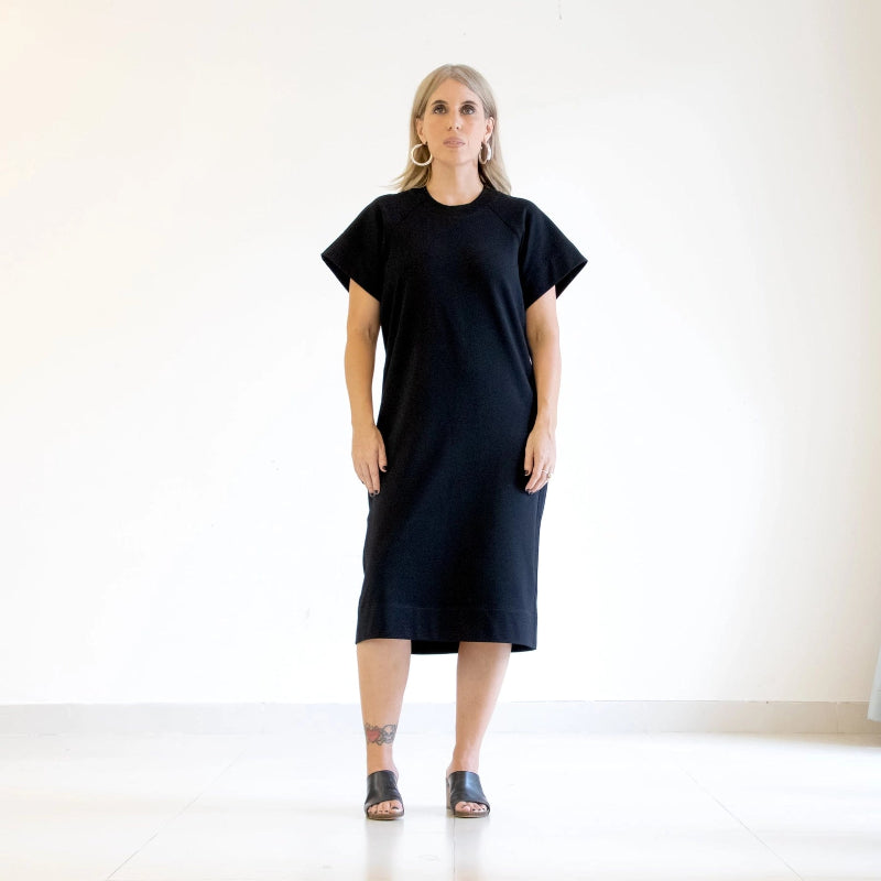 person wearing a black dress standing against a white background