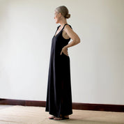 person wearing a black dress standing against a plain wall.
