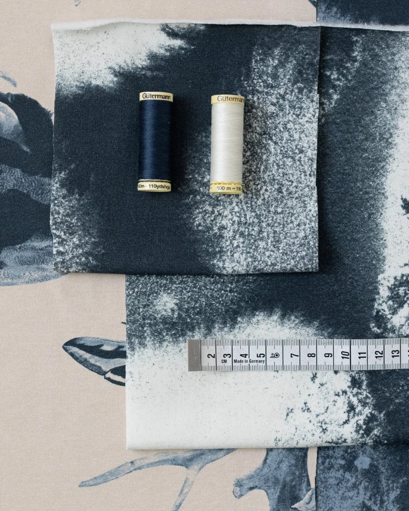 Two spools of thread on a textured fabric background with a ruler for scale.