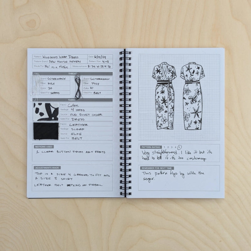Open notebook on a wooden surface with fashion sketches and notes.
