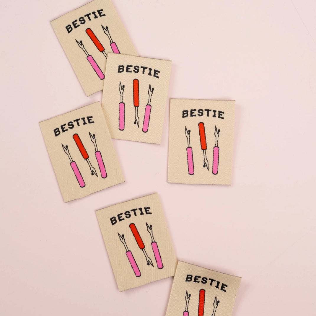 Five 'Bestie' labels with illustrations of pink and red seam rippers on a light pink background