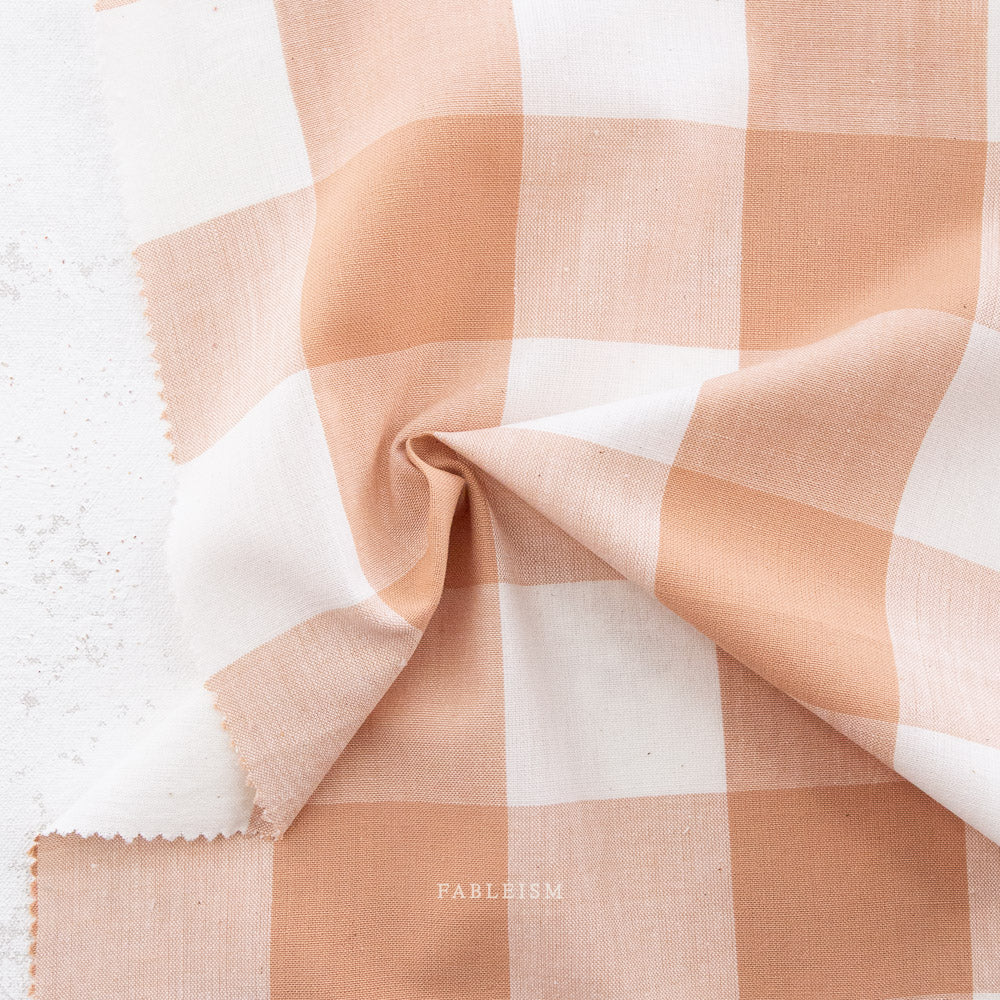 Pink and white gingham fabric swatch on a marble background