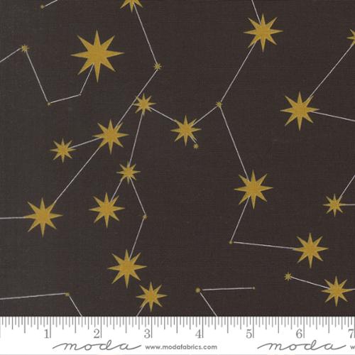 Fabric with gold colored stars and white constellation lines connecting them, on a black background with a ruler at the bottom.