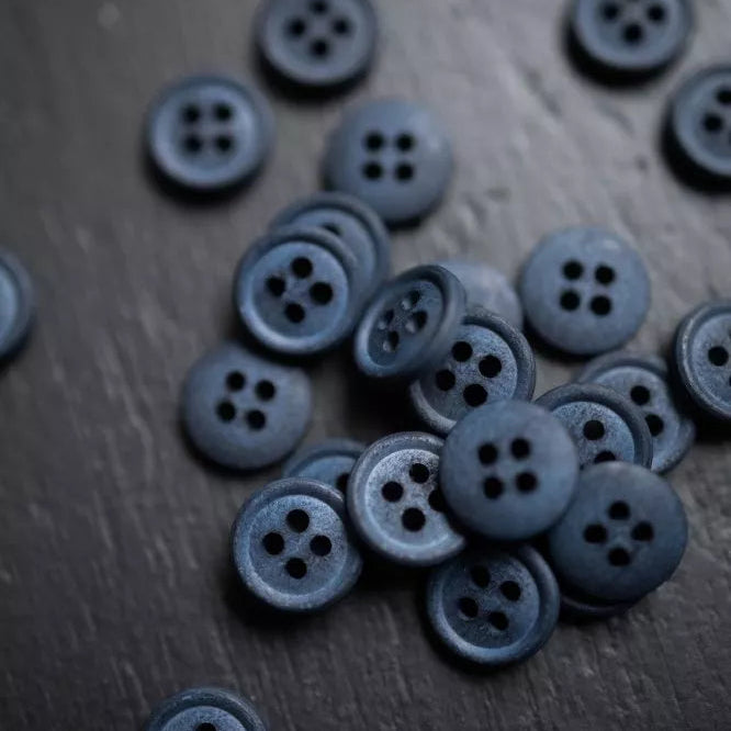 Collection of dark blue buttons on a wooden surface