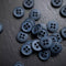Collection of dark blue buttons on a wooden surface