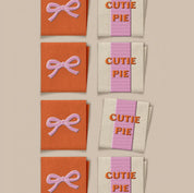 Fabric swatches with 'Cutie Pie' text and pink bows on an orange and beige background