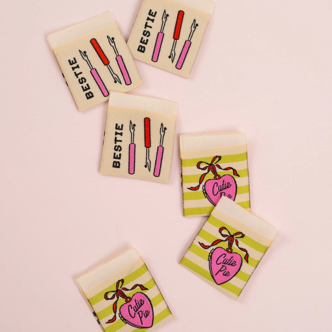 Set of six small labels with striped patterns and decorative elements on a light pink background