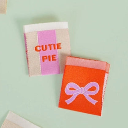 Colorful garment labels with a 'Matchy Matchy Sewing Club' package on a light green background