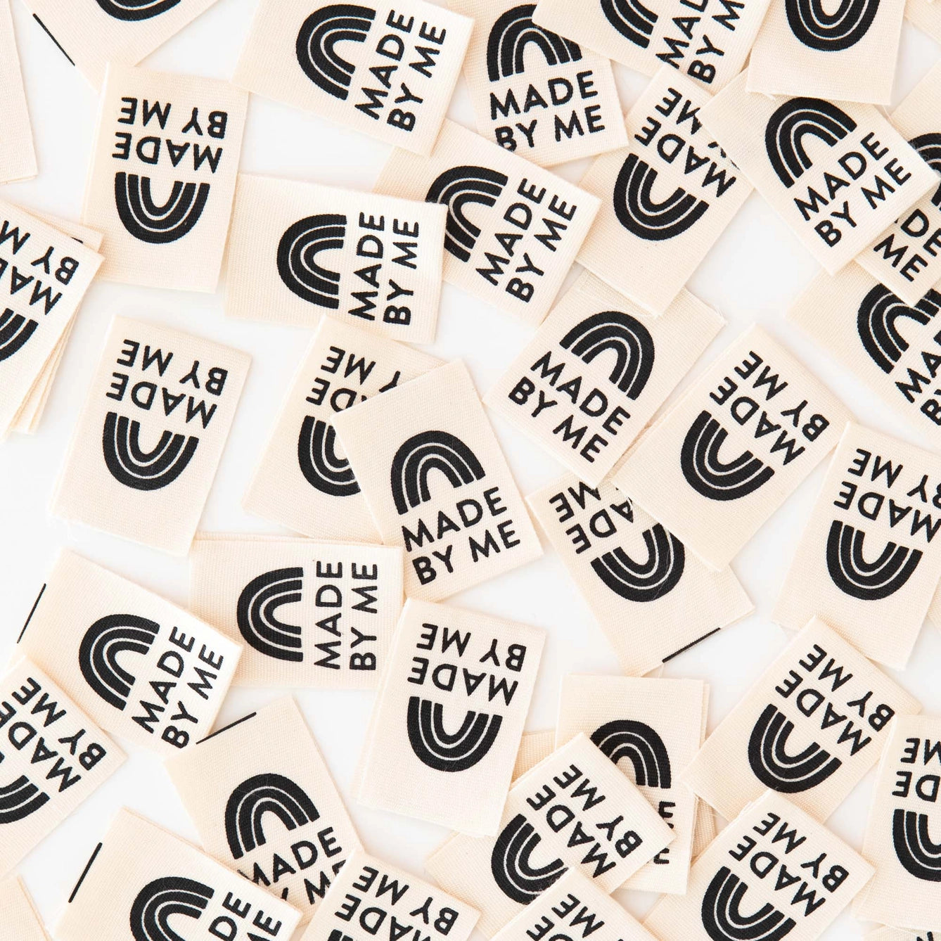 Collection of wooden stamps with 'MADE BY ME' text and rainbow design on a beige background.