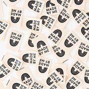 Collection of wooden stamps with 'MADE BY ME' text and rainbow design on a beige background.