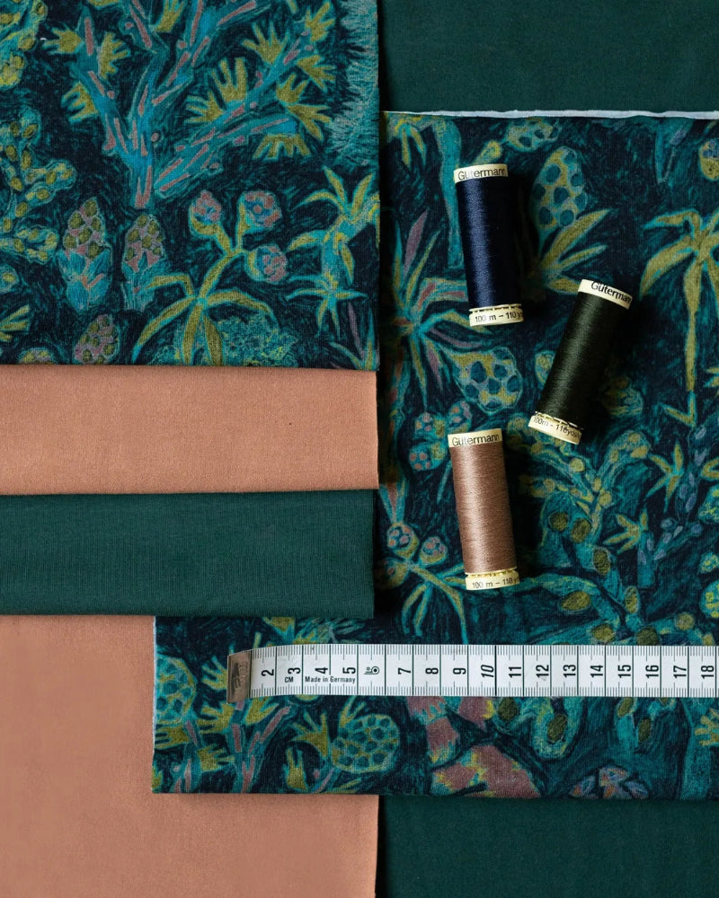 Fabric swatches with floral patterns, spools of thread, and a measuring tape.