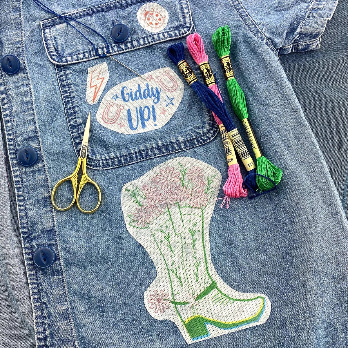 Embroidered cowboy boot patch on a denim jacket with embroidery threads and scissors.