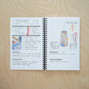 Open notebook with design sketches and notes on a wooden surface