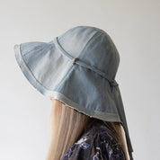 Light blue sun hat with a tie on a neutral background