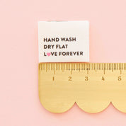 Fabric tag with care instructions on a pink background