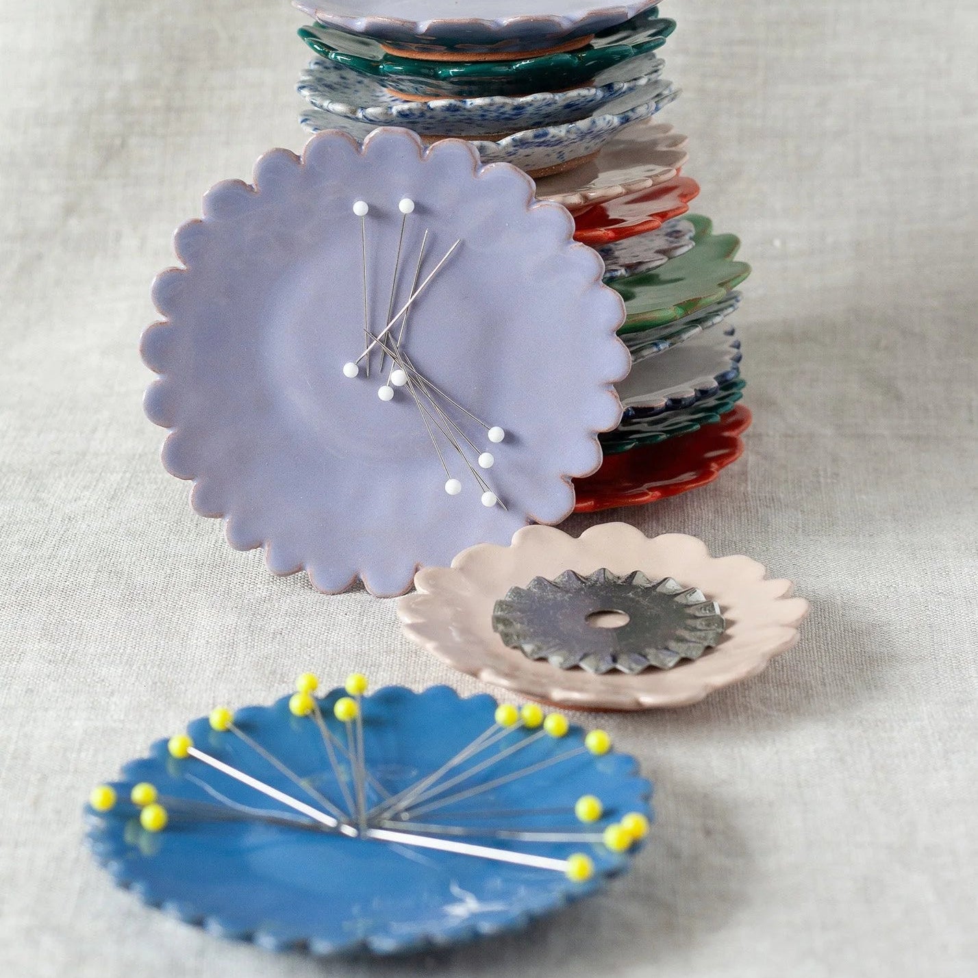Stack of colorful ceramic pin dishes on a light gray background