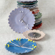 Stack of colorful ceramic pin dishes on a light gray background