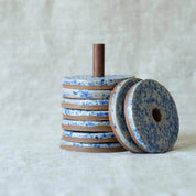 Stack of blue and brown ceramic discs on a textured white background