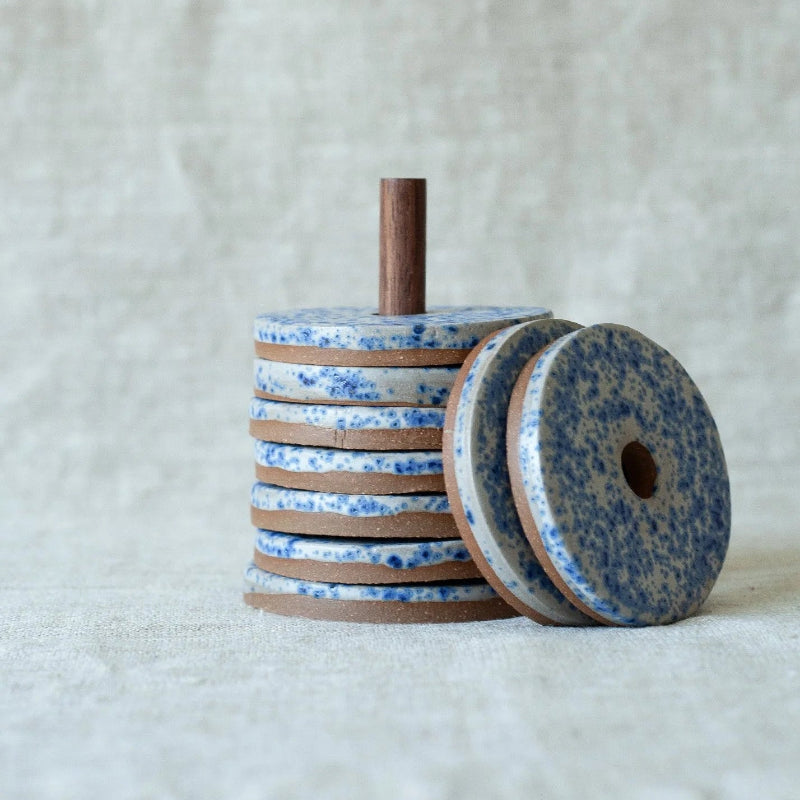 Stack of blue and brown ceramic discs on a textured white background