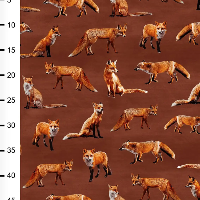 Pattern of foxes on a brown fabric with a ruler on the side.